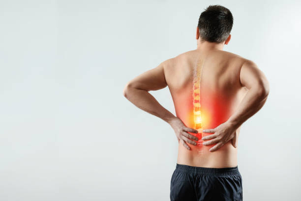 Rear view, the man holds his hands behind his back, pain in the back, pain in the spine, highlighted in red. Rear view, the man holds his hands behind his back, pain in the back, pain in the spine, highlighted in red. Light background. The concept of medicine, massage, physiotherapy, health. back pain stock pictures, royalty-free photos & images