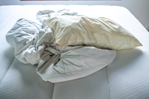 istock White crumpled bed sheet, Ivory pillow on white bed, Close up shot, Selective focus, Bedroom cleaning concept 1143186618