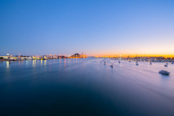 Lights of Port of Tauranga and harbor at dawn Defocused lights of Port of Tauranga ships and harbor at dawn with golden glow of sun on horizon. tauranga new zealand stock pictures, royalty-free photos & images
