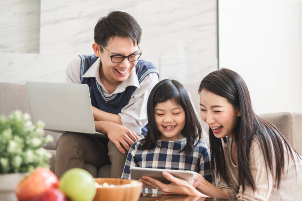 happy asian family using tablet, laptop for playing game watching movies, relaxing at home for lifestyle concept - father digital tablet asian ethnicity daughter imagens e fotografias de stock