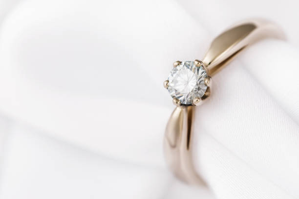 istock Golden wedding ring with a large diamond on a silk fabric with copy space, close-up 1143198046