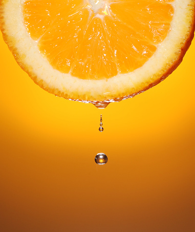 Juice dripping from half slice of orange