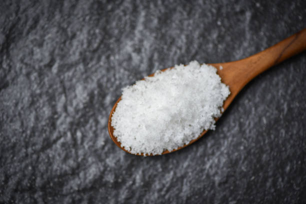 istock Salt in wooden spoon on the dark background 1143199070