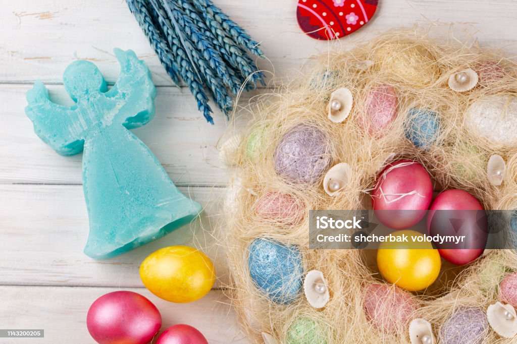 Easter eggs and angel candle on rustic wooden table. Holiday background. Easter eggs and angel candle on light rustic wooden table. Holiday background. Abstract Stock Photo