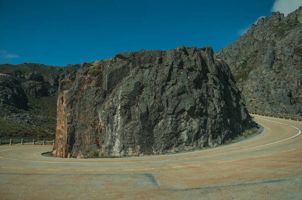 istock Roadway going around a rock on hilly landscape 1143202807