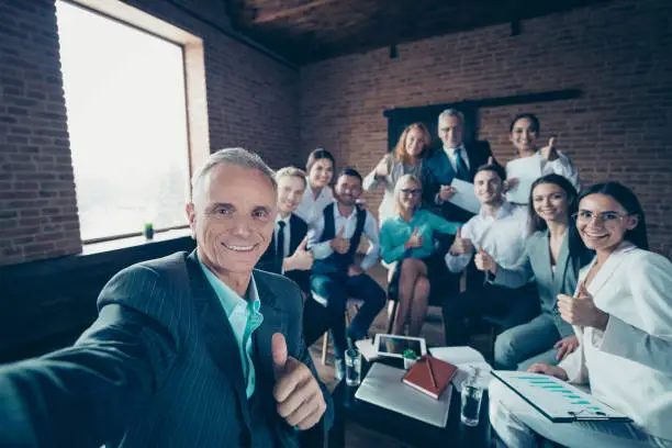 Photo of Self-portrait of nice stylish elegant classy cheerful specialists executive corporate staff showing thumbup yes goal achievement at modern industrial loft interior work place space