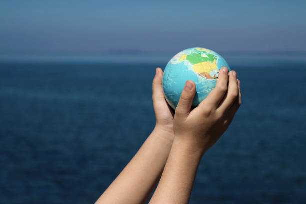 istock World in hands lifted up against the sea 1143206196