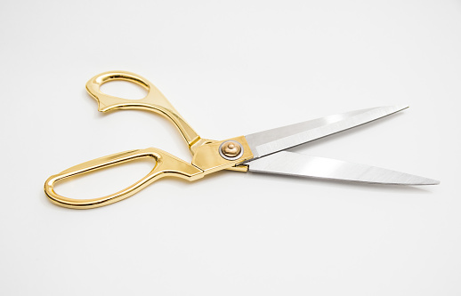 golden metal scissors for cutting lie on a white background