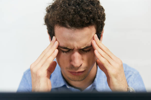 Head in his hands, a young man frowns, eyes closed