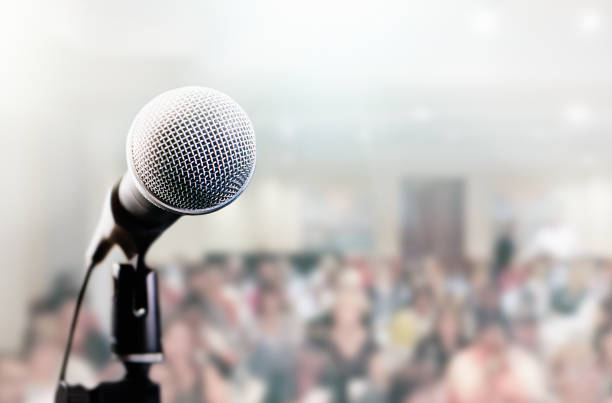istock Vocal microphone on stand with large defocused audience behind 1143212654