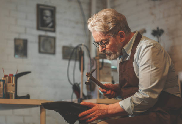 An elderly shoemaker in the workshop stock photo
