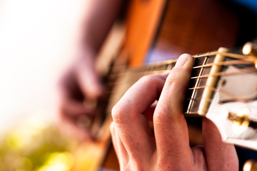 Man playing a top-quality acoustic guitar. Shallow depth of field. Camera: Canon EOS 1Ds Mark III.