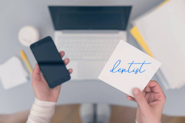 istock Woman clerk is sitting at office table holding note sticker with reminder dentist 1143215537