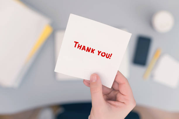 frau sachbearbeiter im büro hält papieraufkleber mit dem wort: danke!  der begriff - label sign symbol single word stock-fotos und bilder