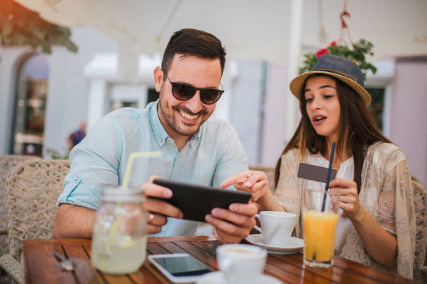 istock Happy young couple shopping online while sitting in a cafe. 1143218521