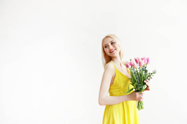 istock Attractive young woman posing over grey background with flowers. 1143221692