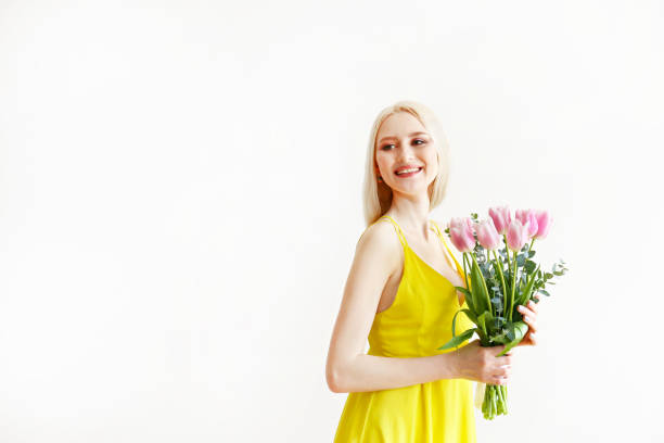 istock Attractive young woman posing over grey background with flowers. 1143221700
