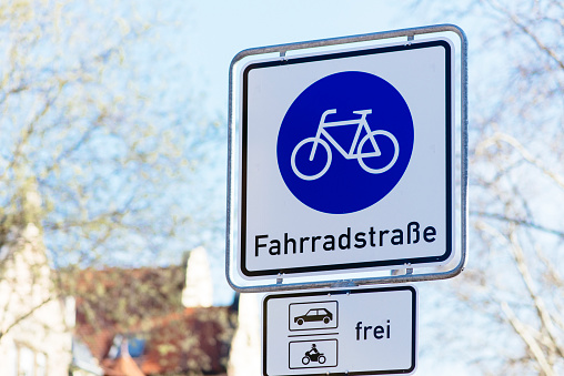 Yellow colored direction sign board against red colored roadblock