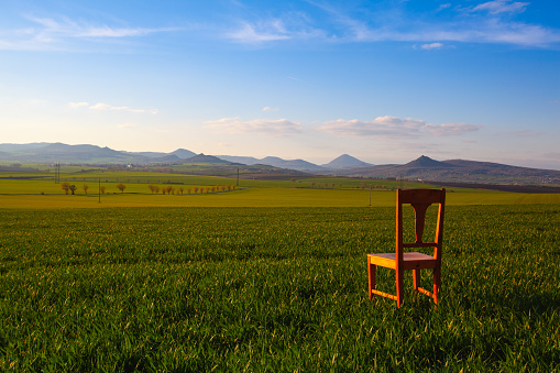 Sunset with old chair in the spring field in Central Bohemian Highlands, Czech Republic. Central Bohemian Uplands  is a mountain range located in northern Bohemia. The range is about 80 km long