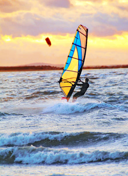 Windsurfer sailing at sunset, West Wittering. Wearing wetsuit.