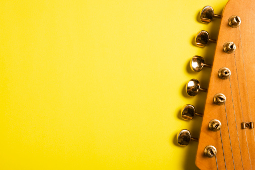Detail of a tuning post on the wooden headstock of an electric bass guitar.