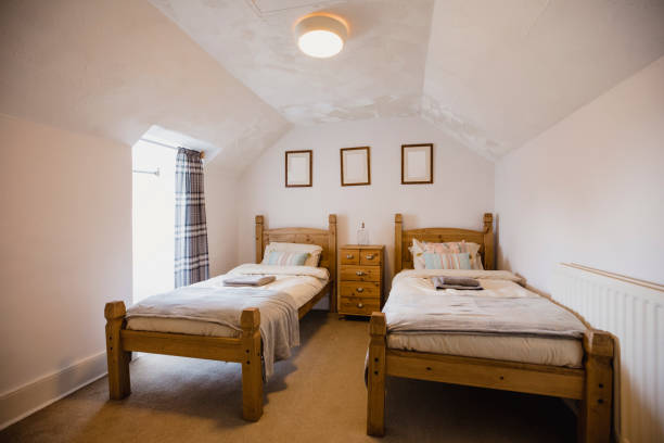 Interior Empty Bedroom Interior shot of a empty bedroom. There are two single wooden beds against a wall with a set of drawers between them. twin bed stock pictures, royalty-free photos & images