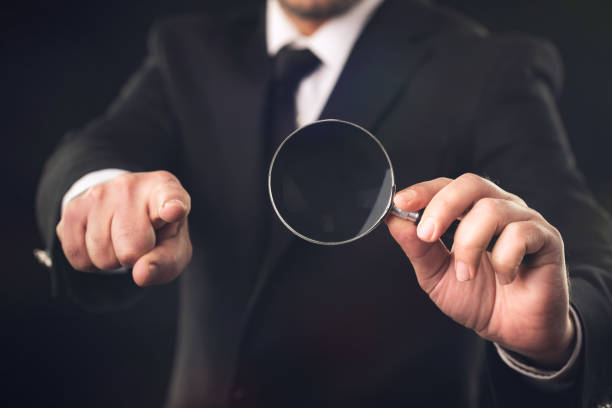 istock Businessman with Magnifying Glass on Dark Background Pointing His Finger, Labor and Workforce Concept 1143231889