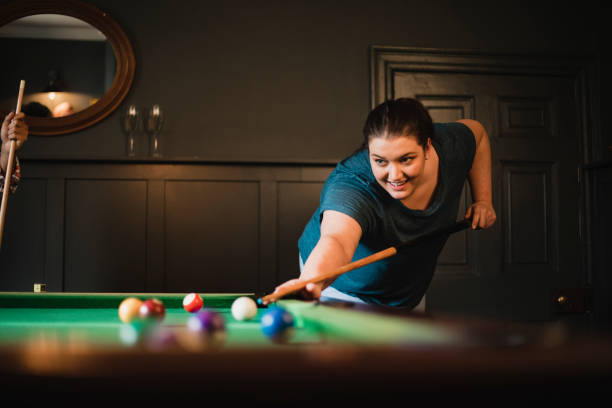 One in the Pocket! Small group of female friends playing a game of pool in a games room in a house. college dorm party stock pictures, royalty-free photos & images