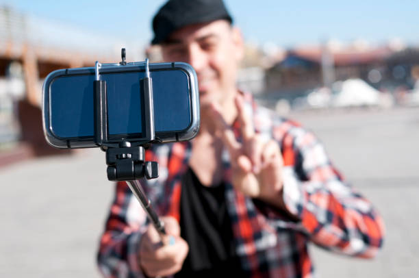 istock young man taking a selfie with a monopod 1143233036