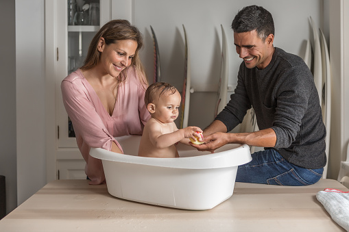 Parents bathing the baby in the bathtub at home