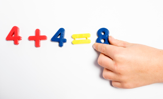 Small boy's hand doing sums with magnetic letters on a magnetic whiteboard. Camera: Canon EOS 1Ds Mark III. 