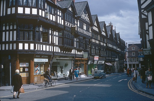London, England, UK, 1972. Street scene with old half-timbered houses in London. Furthermore: Shops, passers-by, advertising signs and store windows.