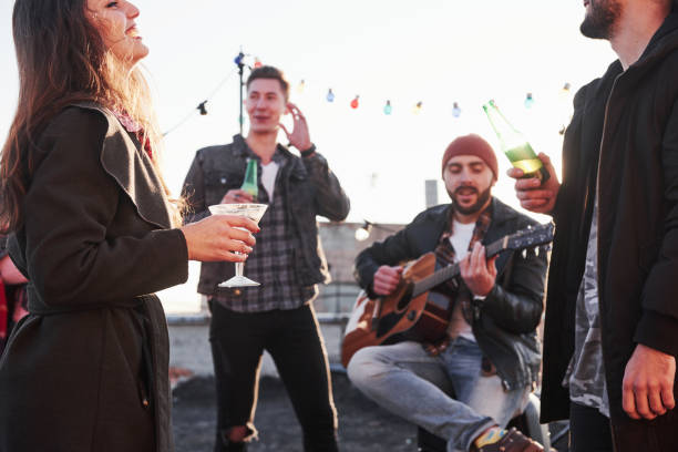 istock Joyful time. Rooftop party with some alcohol drinking and guitar playing. Sunshine behind 1143235041
