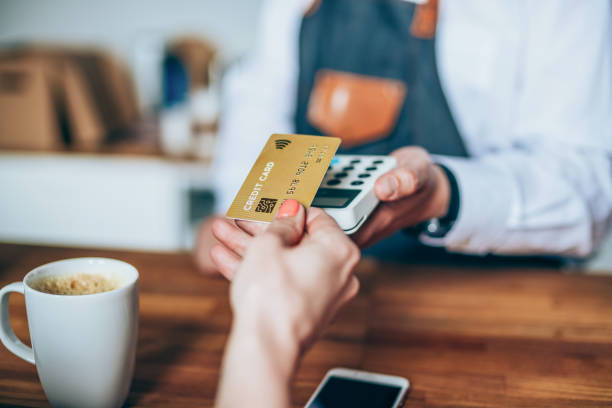 Contactless payment using a credit card Shot of a female customer making contactless or wireless payment approaching stock pictures, royalty-free photos & images