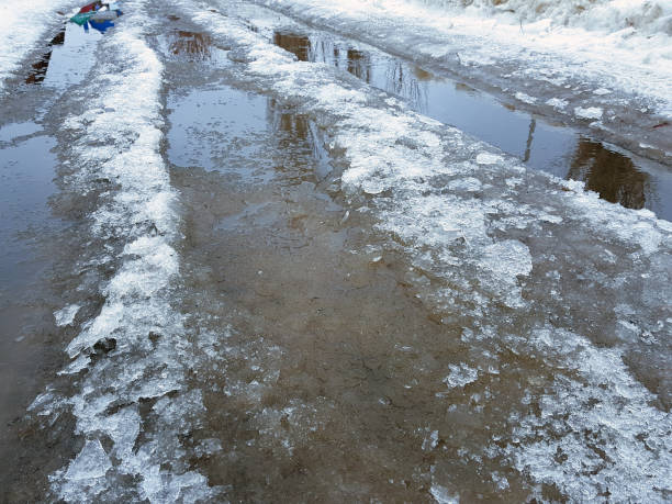 istock Beautiful puddles with ice crust, snow and reflection in winter or spring 1143237394