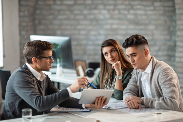 istock Financial advisor and young couple using touchpad on a meeting. 1143237845
