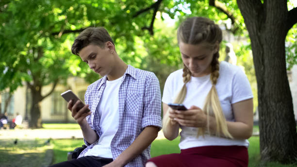 istock Indifferent teenagers scrolling smartphones in park, gadget addiction problem 1143237855