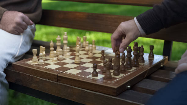 istock Grandfathers playing chess on bench, moving figures on board, game beginning 1143239063
