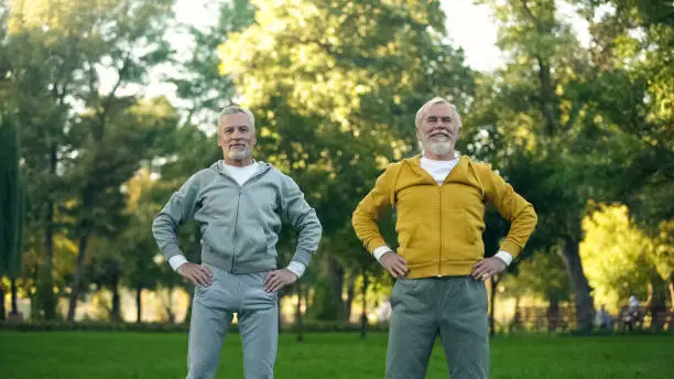 Athletic grandfathers doing morning exercises in park, fitness activity wellness