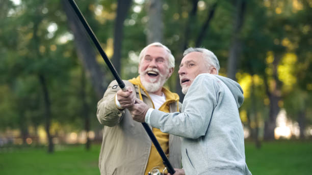istock Two pensioners catching big fish, pulling spinning together, friendship support 1143239192