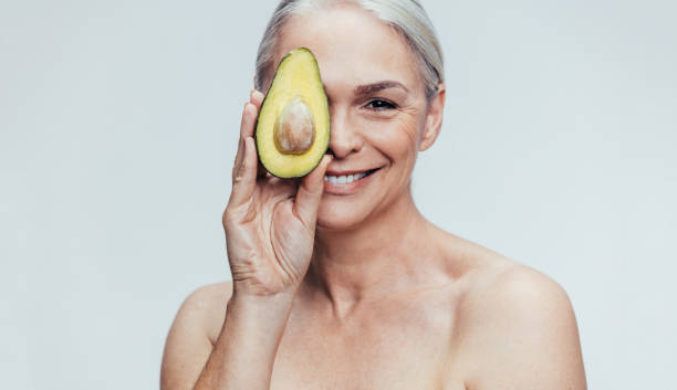 seniorin mit einer halben avocado - beauty sw stock-fotos und bilder