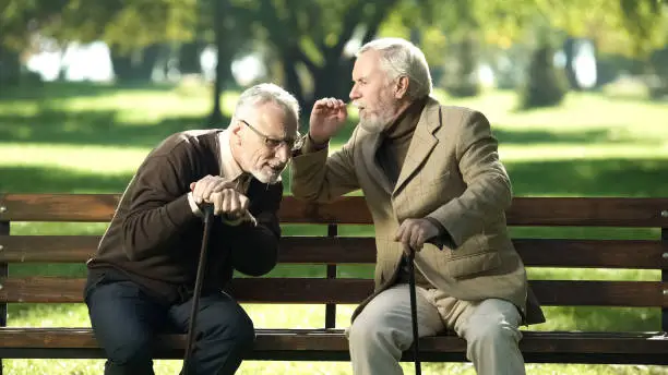Senior gentlemen talking to his hearing impairment old friend, health problems