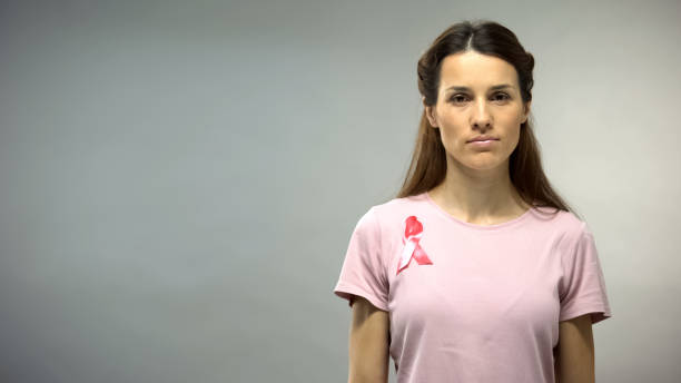 леди с розовой лентой на груди глядя в камеру, концепция рака молочной железы - breast cancer pink ribbon alertness стоковые фото и изображения