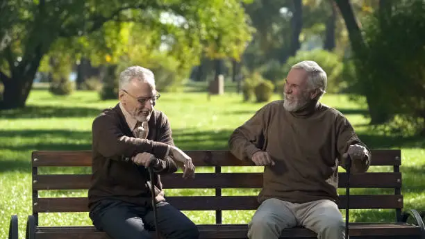 Two senior friends laughing and remembering past days spending time in park