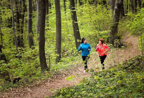 スポーツ ウエアを着ていると山で森で実行されている母と娘 - active seniors women senior adult mature adult ストックフォトと画像