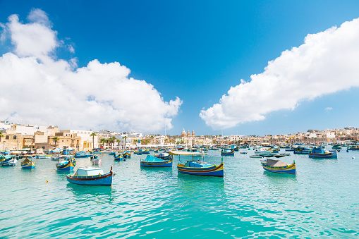 Colourful boats in Marsaxlokk. Clear sky with few clouds on the background.
