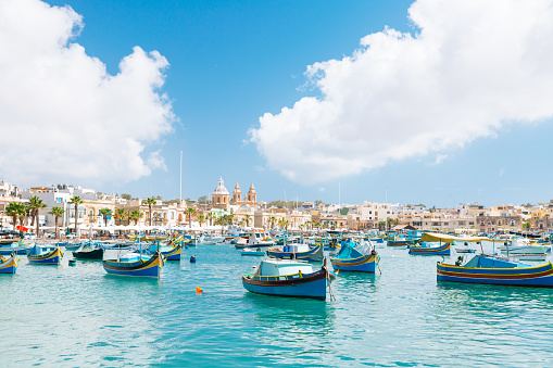Colourful boats in Marsaxlokk. Clear sky with few clouds on the background.