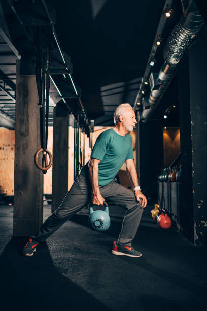 istock Active elderly male doing a one arm kettlebell exercise in a gym gym 1143241246