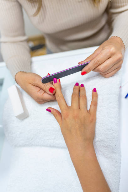 Woman using a buffer for file nail. Closeup shot of a woman in a nail salon receiving a manicure by a beautician at nail salon. Woman using a buffer for file nail. Shallow depth of field with focus on nailfile. nail salon uk stock pictures, royalty-free photos & images