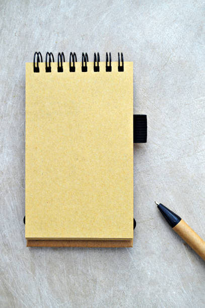 plaine blanc jaune beige page d’un bloc-notes vertical ouvert relié spirale et brun et noir stylo de couleur placé sur le côté, sur un aspect en bois beige couleur grungy vintage fond vertical. - spiral notebook ring binder old paper photos et images de collection